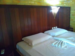 巴拉多库努Pousada do Forte的两张带白色床单和墙壁灯的床