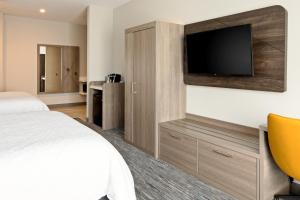 棕榈荒漠Holiday Inn Express & Suites Palm Desert - Millennium, an IHG Hotel的配有一张床和一台平面电视的酒店客房