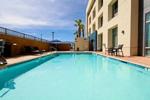 棕榈荒漠Holiday Inn Express & Suites Palm Desert - Millennium, an IHG Hotel的一座带椅子的大型蓝色游泳池和一座建筑