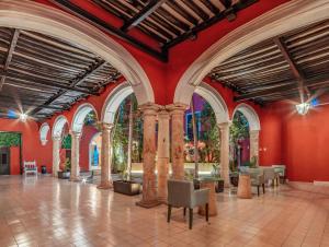 梅里达Hotel HO Merida的大房间,设有红色的墙壁和柱子