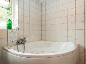 法贾德嘉德7 person holiday home in Ulfborg的浴室铺有白色瓷砖,配有浴缸。