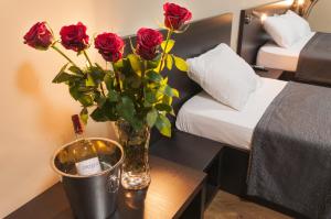 桑丹斯基帕塔利亚家庭酒店的在酒店房间桌子上放着玫瑰花瓶