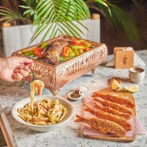 马特鲁港Fouka bay luxurious chalet的一张桌子,上面放着一碗意大利面和一盘肉