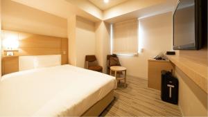 东京Via Inn Higashiginza的一间酒店客房,配有一张白色的床和一张书桌