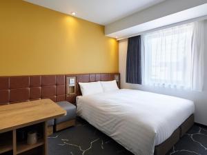 大阪Via Inn Shinsaibashi的小房间设有一张床和一张书桌