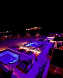 卡拉法蒂斯Aurora Mykonos Villas的夜间带两个游泳池的度假村