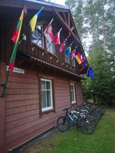 帕卢舍Palūšės Kempingas (kambariai)的停在有旗帜的建筑外的一群自行车