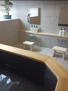妙高Myoko Forest Lodge的带浴缸、镜子和2把凳子的浴室