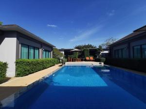 查龙BaanMee Phuket SHA Plus的一座大型蓝色游泳池,位于房子旁边