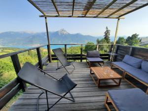 Saint-ApollinaireChalet bioclimatique avec vue sur le lac de Serre Ponçon的木制甲板配有椅子、沙发和桌子