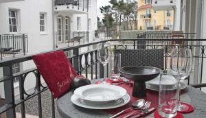 巴贝Haus Meeresblick - Ferienwohnung Lachmoewe A 1.35 (Ref. 162722 u 1)的阳台上的桌子上摆放着盘子和酒杯
