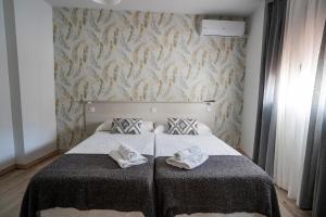 卡塞雷斯Hostal Plaza de Italia的一间卧室配有一张床,上面有两条毛巾