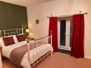 惠特比Underhill Holidays - Underhill Holiday Cottage的一间卧室配有一张带红色窗帘的床和一扇窗户