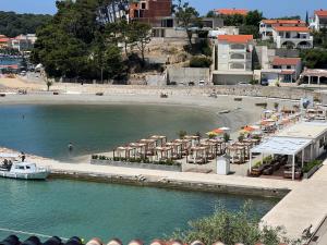 拉布Villas Arbia - Margita Beach hotel的海滩上设有遮阳伞和水上船只
