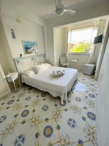 伊斯基亚La Bicocca di Annavì的卧室设有白色的床,铺有蓝色和白色的地板。