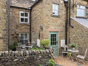 伊姆Carr’s cottage Eyam Peak District,的石头房子前面设有桌椅