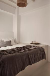 米克诺斯城Maison Central的白色卧室配有一张带黑色毯子的床