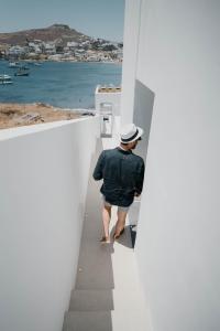 奥诺斯CUBIC Mykonos Seafront Design Suites的沿着白色建筑的楼梯走下的人