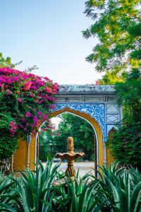 斋浦尔Diggi Palace - A City Center Hidden Heritage Gem的一座拱门,在一座鲜花盛开的桥下,雕像
