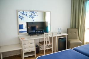 罗列特海岸BPM Lloret Hotel的一间卧室配有一张桌子、一台电视和一张床