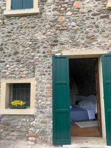 明乔河畔的瓦雷奇奥La Guarnigione的石头建筑中的一张床位,设有绿门和窗户