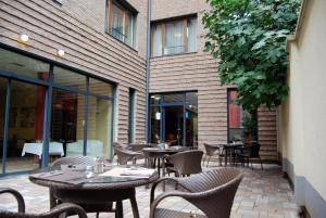 布达佩斯瑞格纳姆酒店的一座配有桌椅的户外庭院和一座建筑