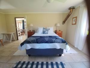 Lions RiverWild Hare Cottages的一间卧室配有一张带蓝色和白色棉被的床