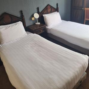安南昆斯伯里阿姆斯酒店的酒店客房内的两张床,配有白色床单