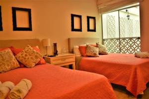 利马Kangaroo Wasi Airport Bed & Breakfast的一间卧室设有两张带橙色床单的床和窗户。