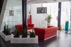 萨洛SALOU 4 YOU apartamentos的大堂设有两把红色椅子和盆栽植物