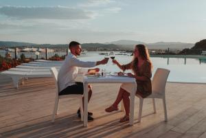 奥尔比亚Hotel dP Olbia - Sardinia的坐在桌子上戴酒杯的男人和女人