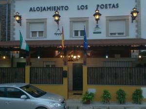 巴埃萨Alojamiento Los Poetas的停在有旗帜的建筑前面的汽车