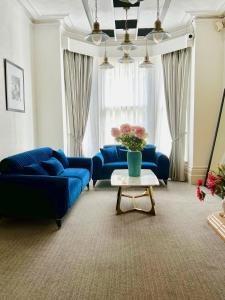 伊斯特布恩Pearl & Pebbles Eastbourne的客厅配有蓝色的沙发和带鲜花的桌子