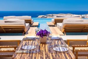天堂海滩Tropicana Hotel , Suites & Villas Mykonos的一张桌子,上面放着眼镜和紫色花瓶