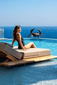 天堂海滩Tropicana Hotel , Suites & Villas Mykonos的坐在水中床边的女人