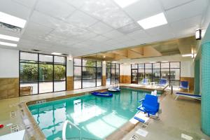 锡考克斯Harmony Suites Secaucus Meadowlands的一个带蓝色椅子和窗户的大型游泳池