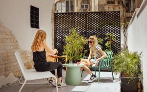 特拉维夫Colorbox Ben Yehuda - Smart Hotel by Loginn Tel Aviv的两名妇女坐在露台上的椅子上