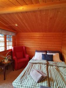 卡尔斯塔德Timber cottages with jacuzzi and sauna near lake Vänern的一间卧室配有一张床和一张红色椅子