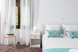 帕纳基雅Whitegold Apartments Panagia的白色卧室配有两张床和一张边桌