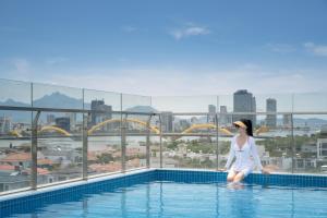 岘港Santori Hotel And Spa的站在游泳池边缘的女人