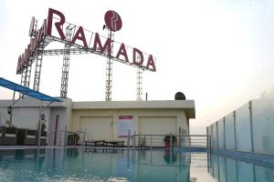 贾朗达尔Ramada by Wyndham Jalandhar City Center的一座建筑物顶部带有标志的游泳池