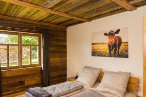 瓦尔德明兴Chalet am Ölberg mit Badefass und Altholzsauna的一间房间,配有一张床和一幅牛的照片