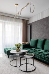 布加勒斯特Urbanstay Suites - Prime Location Designer Suite的客厅配有绿色沙发和2张桌子