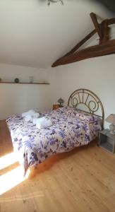 普佐日cheztitoine的一间卧室配有一张带紫色棉被的床