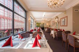 安特卫普安特卫普中心世纪酒店的用餐室配有桌椅和红色餐巾