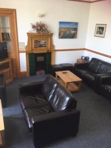 勒威克Islesburgh House Hostel的客厅配有真皮沙发和桌子