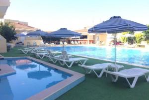 罗德镇Smart Accommodation Rhodes的一个带椅子和遮阳伞的游泳池和一个游泳池