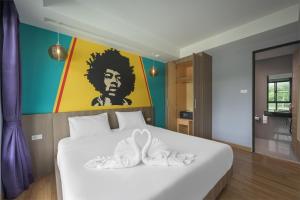 查龙Anchan Boutique Hotel- SHA Plus的卧室配有一张白色床,墙上挂有绘画作品