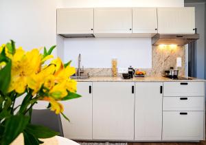 格丁尼亚Valdi Apartament的厨房配有白色橱柜和黄色鲜花