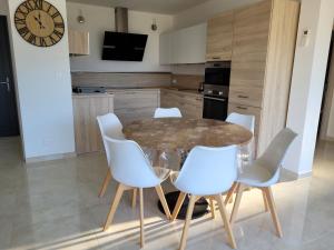 普罗普里亚诺Appartement neuf 3 chambres vue mer Propriano的厨房配有玻璃桌和白色椅子